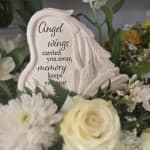 Memorial plaque with angel wings among white flowers
