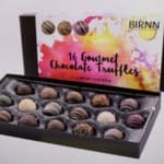 Box of assorted gourmet chocolate truffles with a colorful lid
