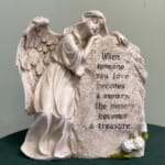 Angel figurine beside a memorial stone with an engraved quote
