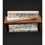 Stacked chocolate caramel boxes on a wooden display stand