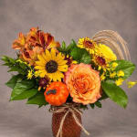 Autumn bouquet with sunflowers, roses, and a small pumpkin in a vase