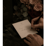 Gift card with a handwritten note beside roses and a pen