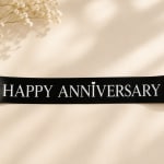 Black anniversary ribbon with white flowers on a cream background