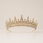 Gold jeweled tiara with clear stones on a plain background