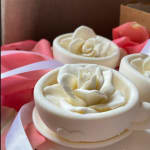 White rose-shaped soaps on pink wrapping with ribbon