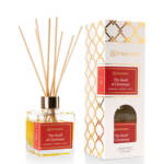 Reed diffuser in a glass bottle beside its box with red labels
