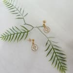 Gold cross earrings on a white textured fabric background