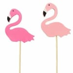 Two pink flamingo cake toppers on sticks against a white background