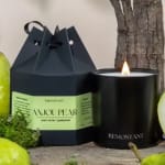 Black candle in a glass jar beside a boxed candle gift set