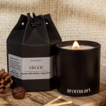 Lit black candle beside a black gift box on a wooden surface