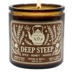 Lit amber candle in a glass jar with a brown label