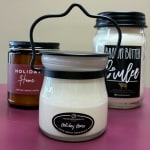 Three scented candles in glass jars, one with a metal handle in front