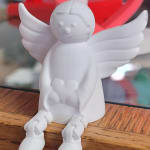 White angel figurine with outstretched wings sitting on a wooden surface