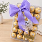 Box of gold-wrapped chocolates tied with a purple ribbon
