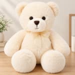 Cream teddy bear with a ribbon bow sitting on a table