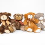 Four plush teddy bears with ribbon bows on a white background