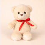 Cream teddy bear with a red ribbon bow on a plain background