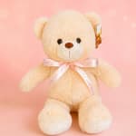 Cream teddy bear with a pink ribbon on a pink background
