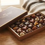 Open box of assorted chocolates on a wooden table