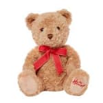 Brown teddy bear with red bow sitting upright on a white background