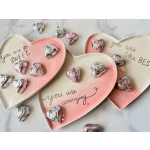 Heart-shaped ceramic plates with sweet messages and foil-wrapped heart chocolates on a light surface