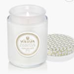 White jar candle with a patterned lid and visible flame