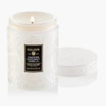 White scented candle in an embossed glass jar with a lid