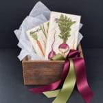 Gift box with two packaged napkins and a wooden crate tied with satin ribbons