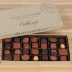 Box of assorted gourmet chocolates on a wooden surface