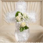 White rose corsage with lace trim and ribbon on a satin cross backdrop