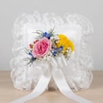 Pink and yellow roses on a white lace pillow with ribbon