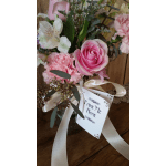 Pink rose and carnations in a glass vase with a ribbon and gift tag