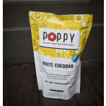 Bag of Poppy white cheddar popcorn on a dark surface
