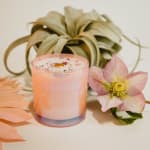 Pink candle with a flower and succulent beside it