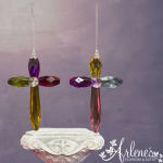 Two colorful crystal cross ornaments hang above a carved pedestal