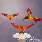 Three crystal hummingbird figurines on a decorative pedestal