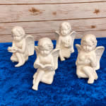 Four ceramic angel figurines on a blue surface