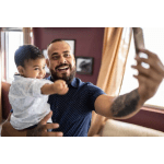 Man holding a child while taking a selfie indoors
