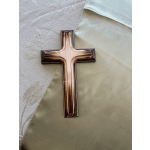 A bronze cross resting on pale embroidered fabric