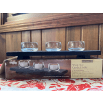 Three glass tealight holders on a dark wood tray.