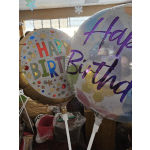 Two colorful round Happy Birthday balloons on white sticks indoors