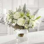 White floral arrangement in a clear glass vase with a white wrap