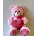 Pink teddy bear holding a red heart with a ribbon
