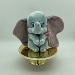 Plush elephant sitting on a gold pedestal stand