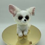 Small white plush dog with large eyes sitting on a gold round base