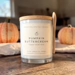 Pumpkin buttercream candle in a glass jar with a wooden lid and spoon