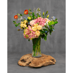 Mixed bouquet of roses, hydrangea, and other blooms in a glass vase