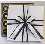 Gift box with black ribbon over a tray of assorted chocolates