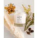 White candle surrounded by dried botanicals and pinecones