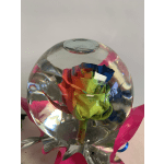 Rainbow-colored rose inside a clear glass orb with pink ribbon accents